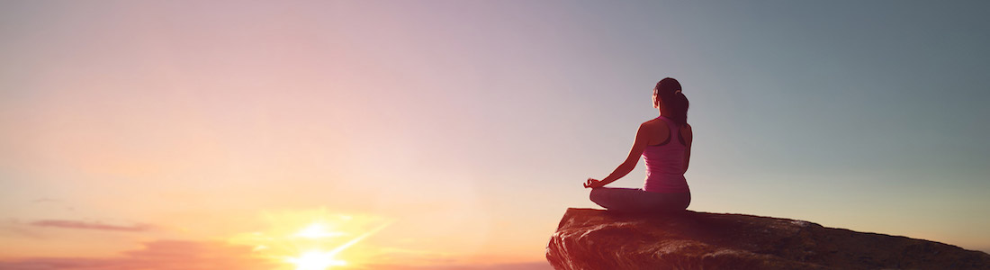 Maui offers beautiful sunsets for tantra yoga meditations Tantra yoga woman sitting on rock at sunset